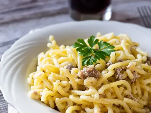 Piatto di pasta con salsiccia sbriciolata, condita con un sugo cremoso e guarnita con prezzemolo fresco.