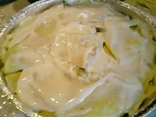 Crespelle con asparagi pronte per essere infornate, ricoperte da una cremosa besciamella.