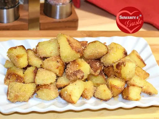 Patate sabbiose in padella, dorate e croccanti, servite su un piatto bianco. Un contorno irresistibile per ogni pasto.
