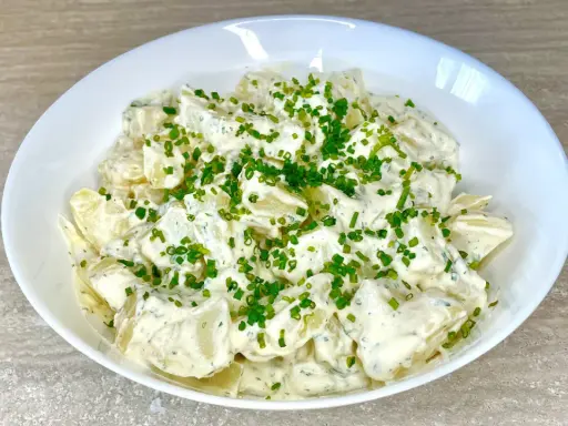 Una cremosa insalata di patate, condita con erbe aromatiche e guarnita con erba cipollina fresca. Perfetta per un picnic o un pranzo leggero.