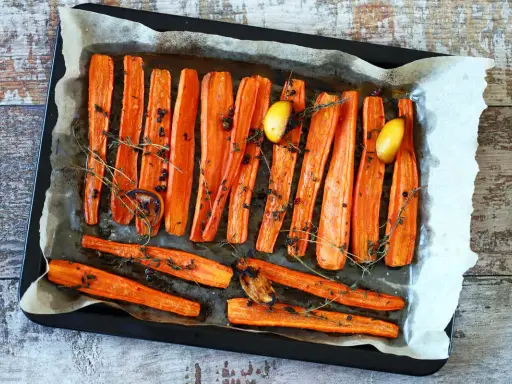 Carote al forno dorate e caramellate, condite con erbe aromatiche, pepe nero e spicchi d'aglio. Un contorno semplice e gustoso.