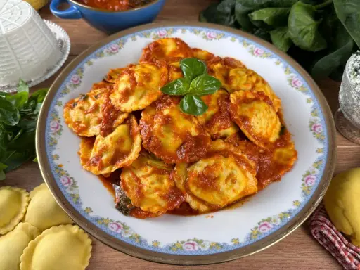 Piatto di ravioli ricotta e spinaci conditi con sugo rosso e basilico fresco. Ingredienti freschi e pasta fatta in casa.