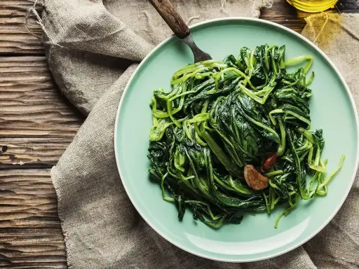 Piatto di puntarelle in padella, condite con aglio e peperoncino, pronte per essere gustate.