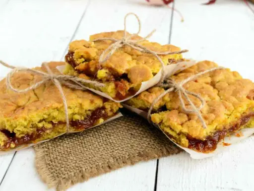 Tre fette di torta con marmellata, legate con spago, su carta da forno e tela di juta.