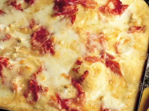 Pizza di patate filante con prosciutto croccante, un piatto invitante e gustoso.