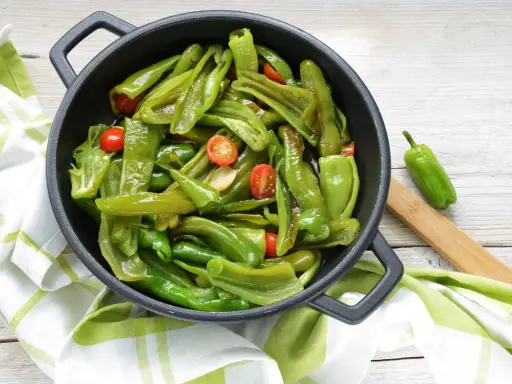 Friggitelli in padella, saltati con pomodorini e aglio, pronti per essere gustati.