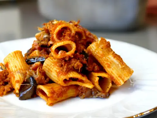Piatto di pasta e melanzane alla napoletana, con rigatoni ricchi di sugo e melanzane fritte.