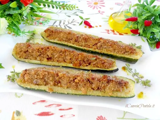 Zucchine ripiene tonno, dorate e croccanti, servite su un piatto bianco con erbe aromatiche.
