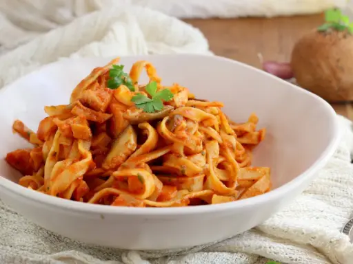 Un piatto invitante di tagliatelle ai funghi, condite con una ricca salsa al pomodoro e guarnite con prezzemolo fresco.