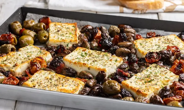 Feta al forno con olive e pomodorini secchi, un piatto saporito e profumato, pronto per essere gustato.
