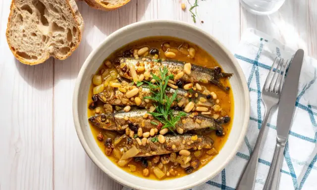 Sarde in saor, un piatto veneziano con sarde, cipolle, pinoli e uvetta, servito in una ciotola con pane rustico.