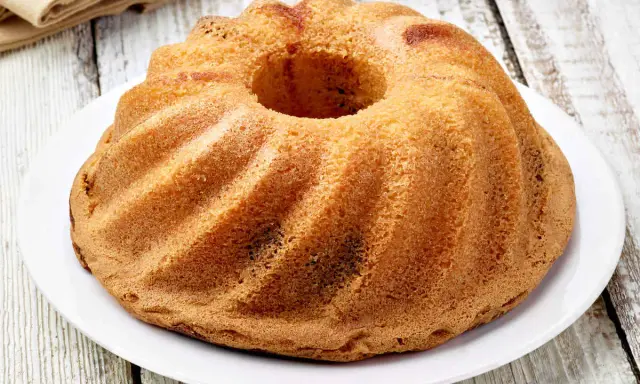 Ciambellone senza uova dorato e soffice, con la sua classica forma a ciambella, pronto per essere gustato.