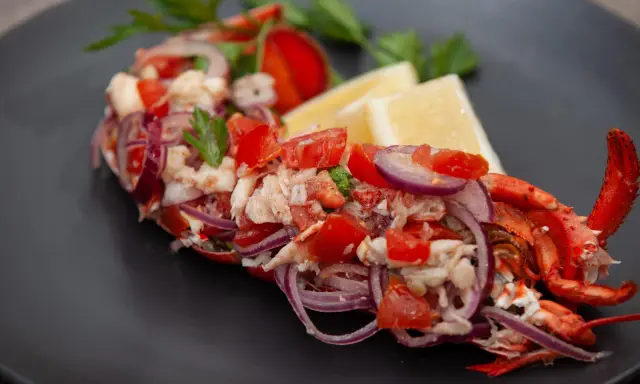 Astice alla catalana: polpa di astice sfilacciata con pomodoro, cipolla rossa e limone, guarnito con prezzemolo.
