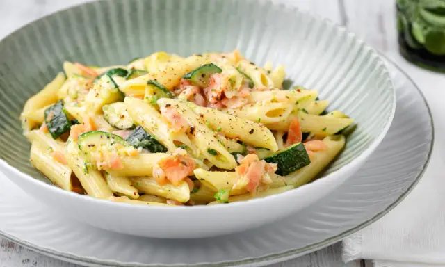 Penne con salmone e zucchine, un piatto cremoso e saporito, condito con erbe fresche e pepe nero.