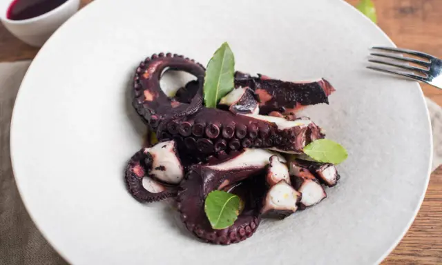 Polpo ubriaco ricetta: tentacoli succulenti e profumati, cotti a puntino e guarniti con foglie di alloro.