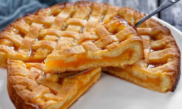Deliziosa crostata senza glutine con ripieno di albicocche, una fetta sollevata da una paletta mostra la morbidezza.