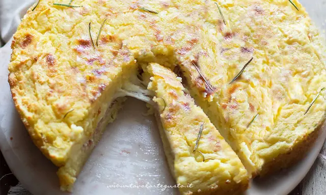 Una fetta di torta di patate filante, dorata e profumata al rosmarino, pronta per essere gustata.