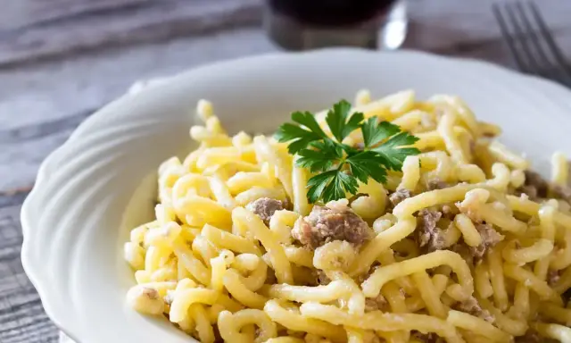Piatto di pasta con salsiccia sbriciolata, condita con un sugo cremoso e guarnita con prezzemolo fresco.