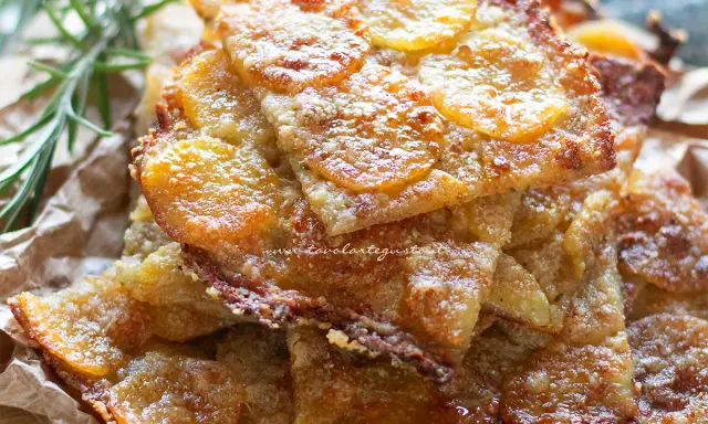 Schiacciata di patate croccante, dorata e invitante, con fette sottili di patate e un tocco di rosmarino.