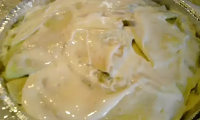 Crespelle con asparagi pronte per essere infornate, ricoperte da una cremosa besciamella.