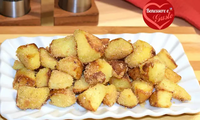Patate sabbiose in padella, dorate e croccanti, servite su un piatto bianco. Un contorno irresistibile per ogni pasto.