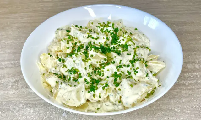 Una cremosa insalata di patate, condita con erbe aromatiche e guarnita con erba cipollina fresca. Perfetta per un picnic o un pranzo leggero.