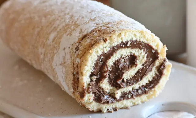 Un soffice rotolo alla Nutella, cosparso di zucchero a velo, pronto per essere gustato.