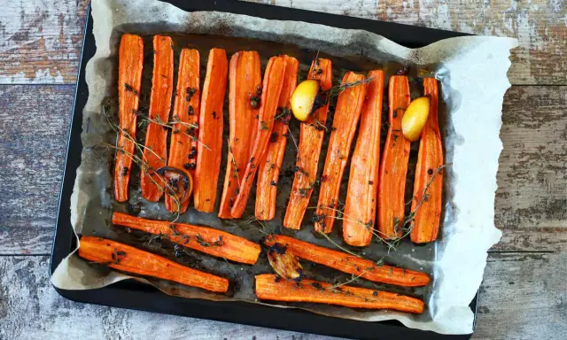 Carote al forno dorate e caramellate, condite con erbe aromatiche, pepe nero e spicchi d'aglio. Un contorno semplice e gustoso.
