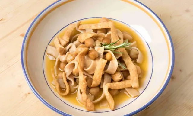 Piatto di ciceri e tria, pasta fresca con ceci e sfoglie fritte, guarnito con rosmarino.