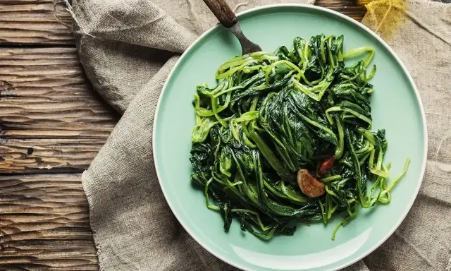 Piatto di puntarelle in padella, condite con aglio e peperoncino, pronte per essere gustate.
