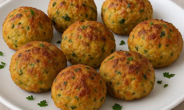 Polpette dorate di zucchine e tonno, guarnite con prezzemolo fresco, pronte per essere gustate.