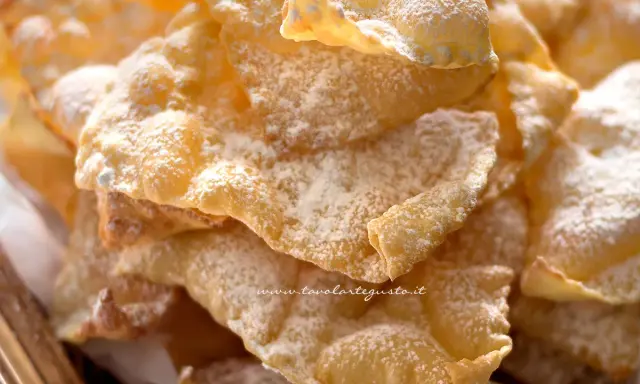Chiacchiere croccanti, dolci e leggere, come quelle della ricetta della nonna, cosparse di zucchero a velo.