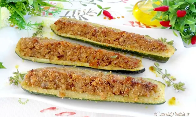Zucchine ripiene tonno, dorate e croccanti, servite su un piatto bianco con erbe aromatiche.
