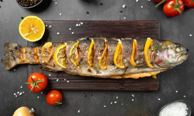 Un succulento pesce alla brace, guarnito con fette di limone e erbe aromatiche, pronto per essere gustato.