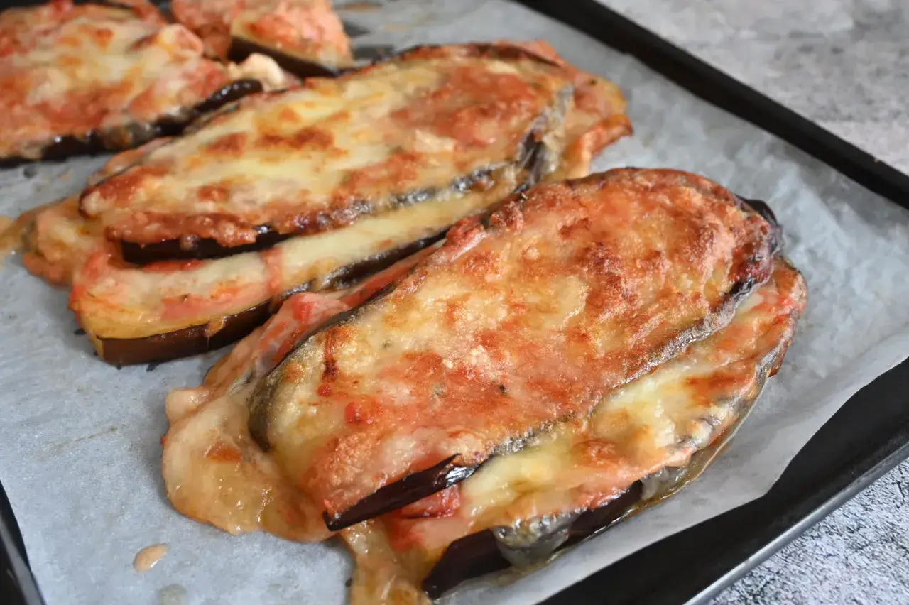 Melanzane al forno gratinate con formaggio filante e pomodoro, pronte per essere gustate.