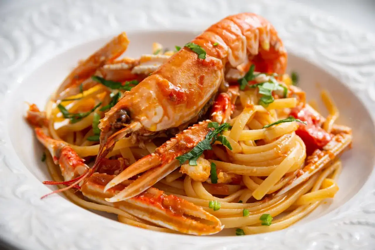 Un piatto invitante di linguine agli scampi, con pasta fresca e scampi succulenti conditi con un sugo rosso e prezzemolo tritato.