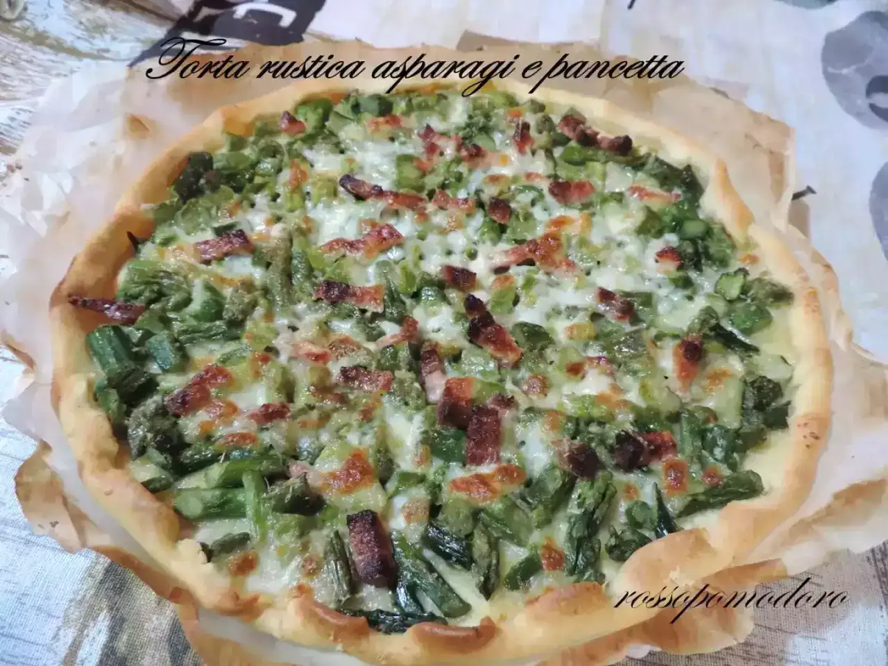 Torta rustica con asparagi e pancetta, un tripudio di sapori primaverili su una base dorata.
