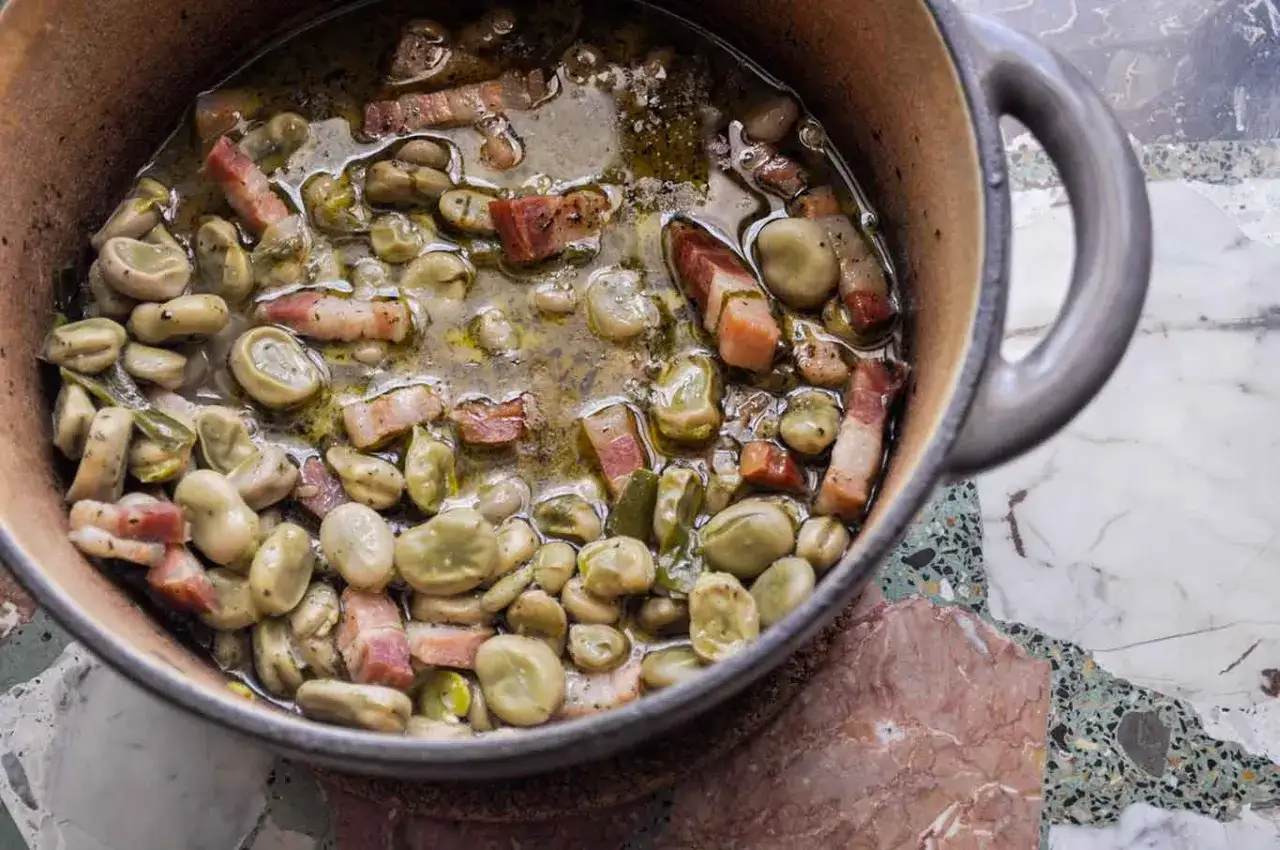 Un saporito piatto di pasta fave e pancetta in una pentola di terracotta, pronto per essere gustato.