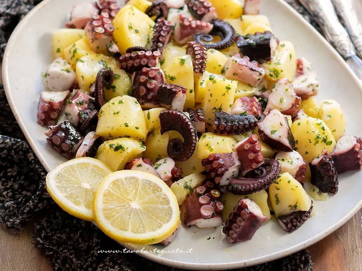 Un saporito polpo con patate, condito con prezzemolo e servito con spicchi di limone.