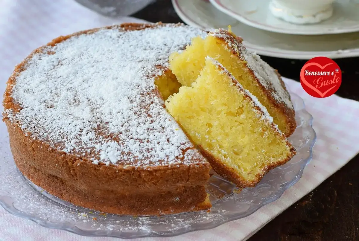 Una deliziosa torta allo yogurt soffice, cosparsa di zucchero a velo, con due fette tagliate per mostrare la sua morbidezza.