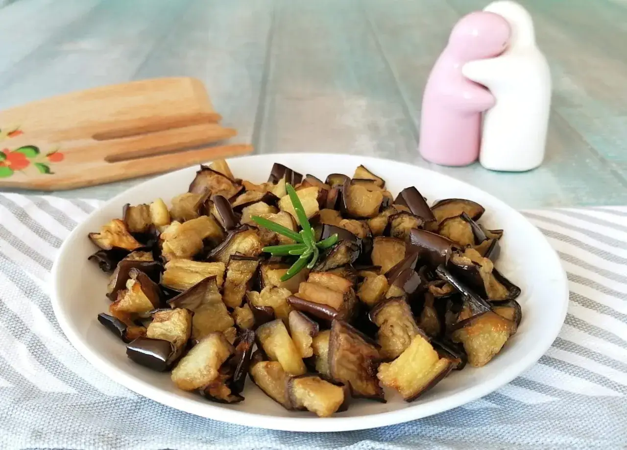 Melanzane dorate e saporite, cotte alla perfezione nella friggitrice ad aria, guarnite con un rametto di rosmarino.