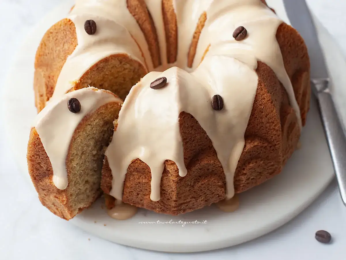 Deliziosa ciambella al caffè con glassa e chicchi di caffè, una fetta è stata tagliata per mostrare la morbidezza.