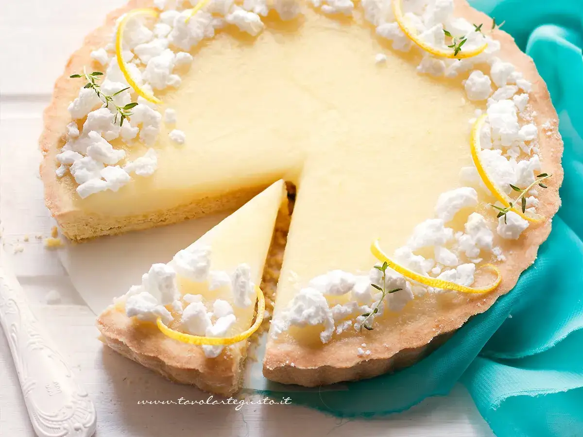 Una deliziosa crostata con crema pasticcera, decorata con meringhe e scorzette di limone, pronta per essere gustata.