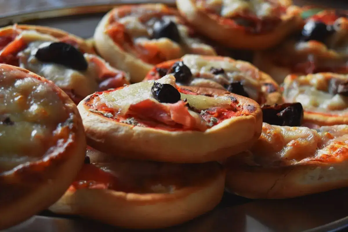 Pizzette fatte in casa, con pomodoro, mozzarella filante e olive nere, pronte per essere gustate.