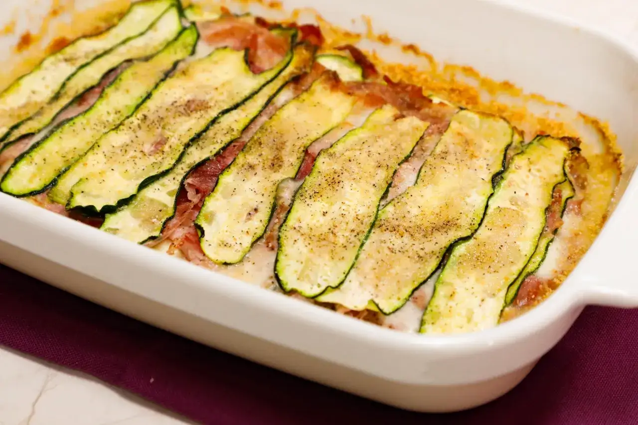Zucchine al forno con mozzarella filante e prosciutto, un piatto saporito e leggero, pronto per essere gustato.
