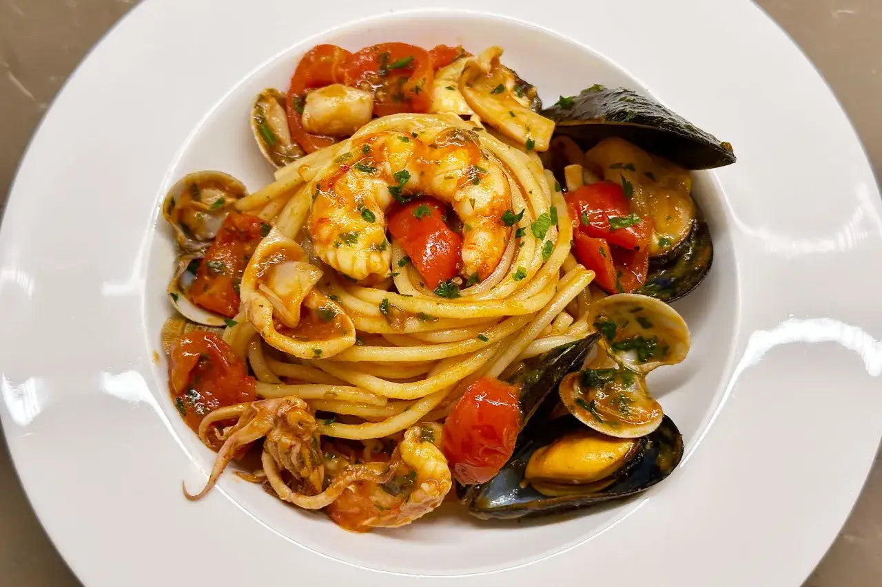 Un piatto invitante di spaghetti allo scoglio, con gamberi, cozze, vongole e calamari in un sugo rosso.