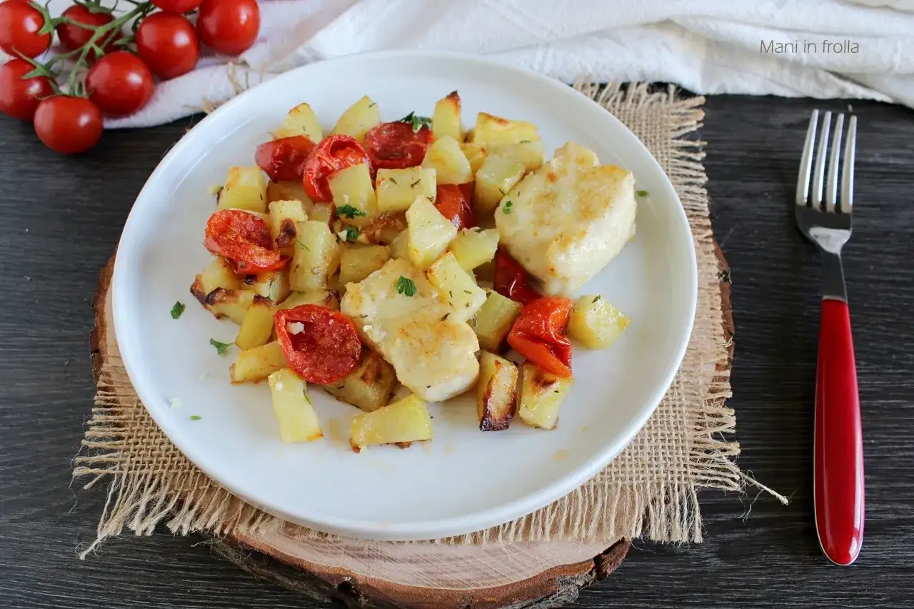 Piatto di merluzzo al forno con patate e pomodorini, guarnito con prezzemolo fresco.