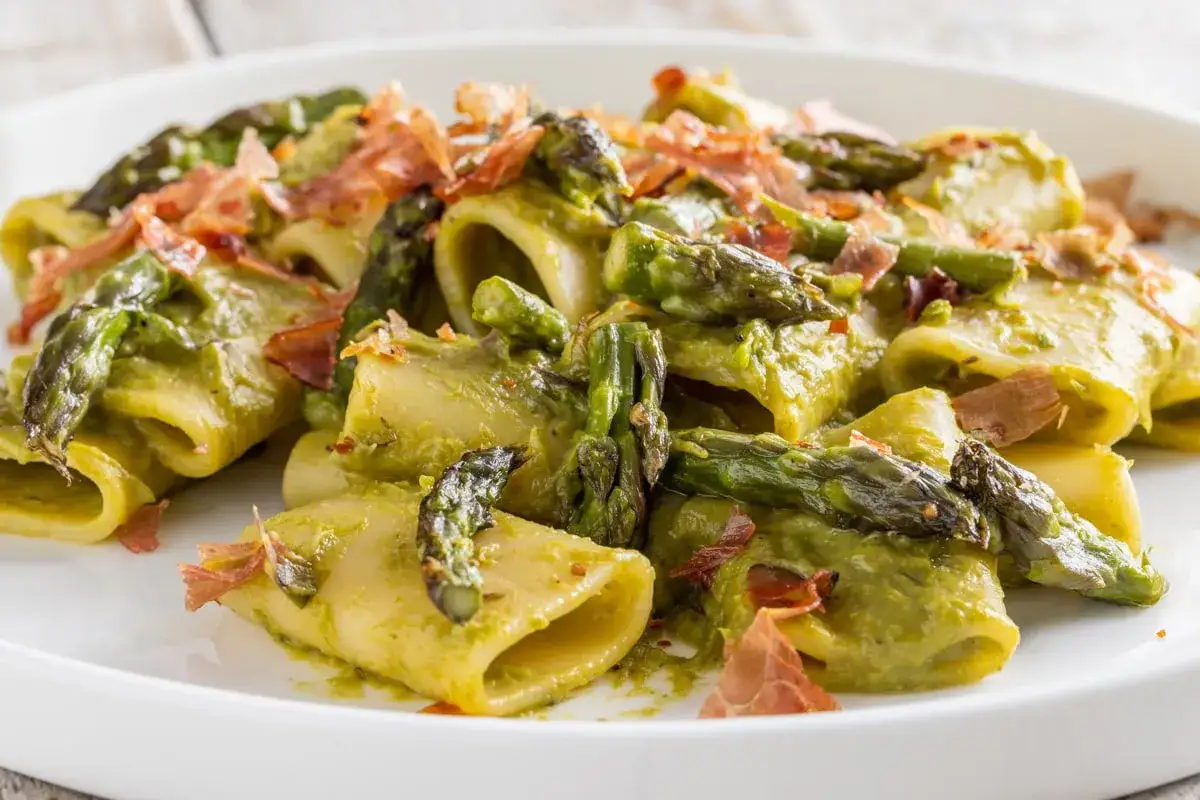 Paccheri conditi con crema di asparagi, punte di asparagi croccanti e scaglie di speck.