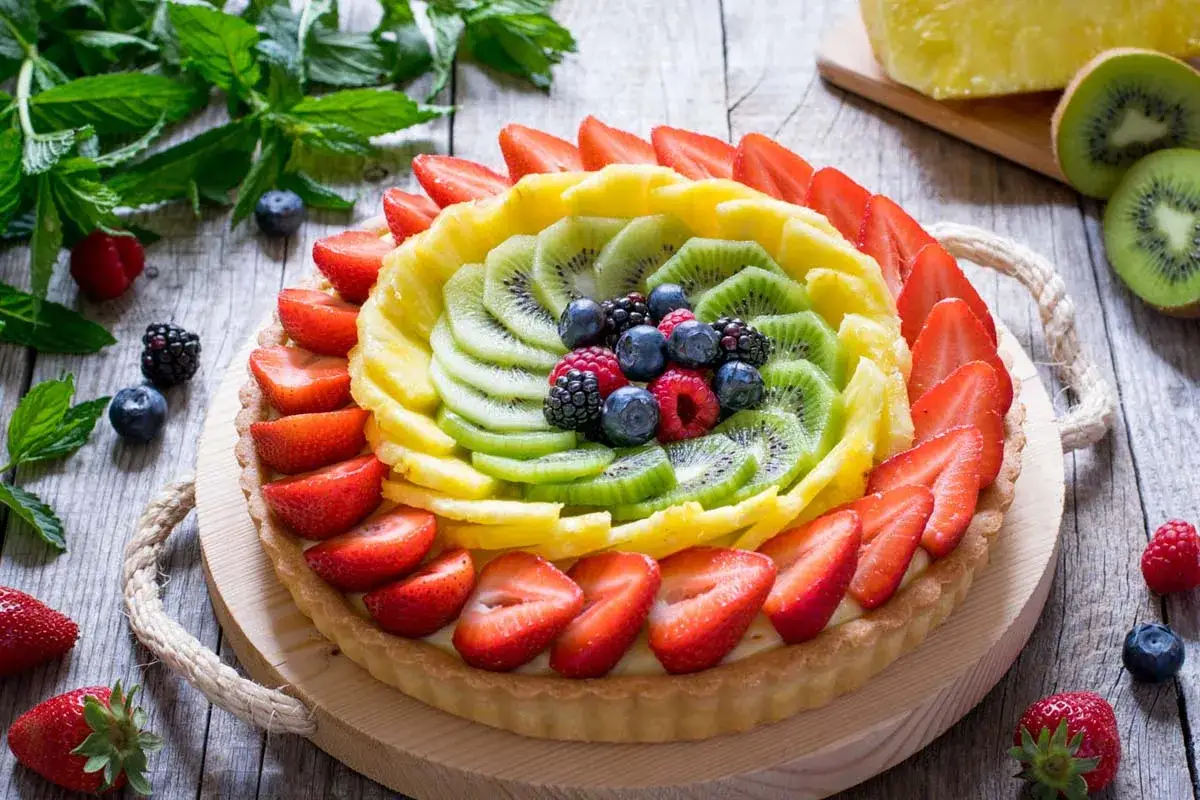 Una colorata crostata di frutta con fragole, kiwi, ananas e frutti di bosco, un tripudio di sapori estivi.