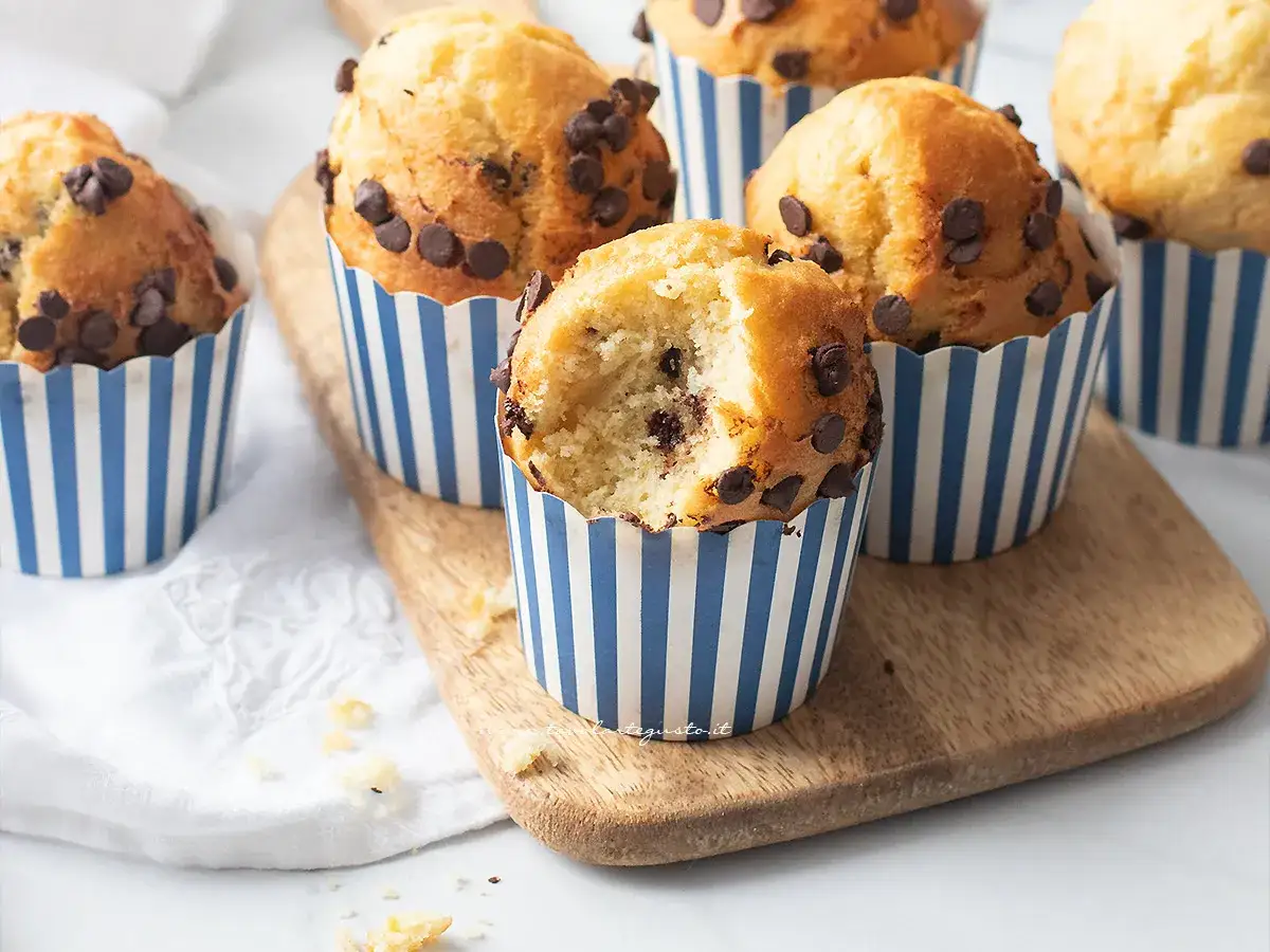 Muffin friggitrice ad aria con gocce di cioccolato, uno &egrave; stato morso rivelando un interno soffice e goloso.